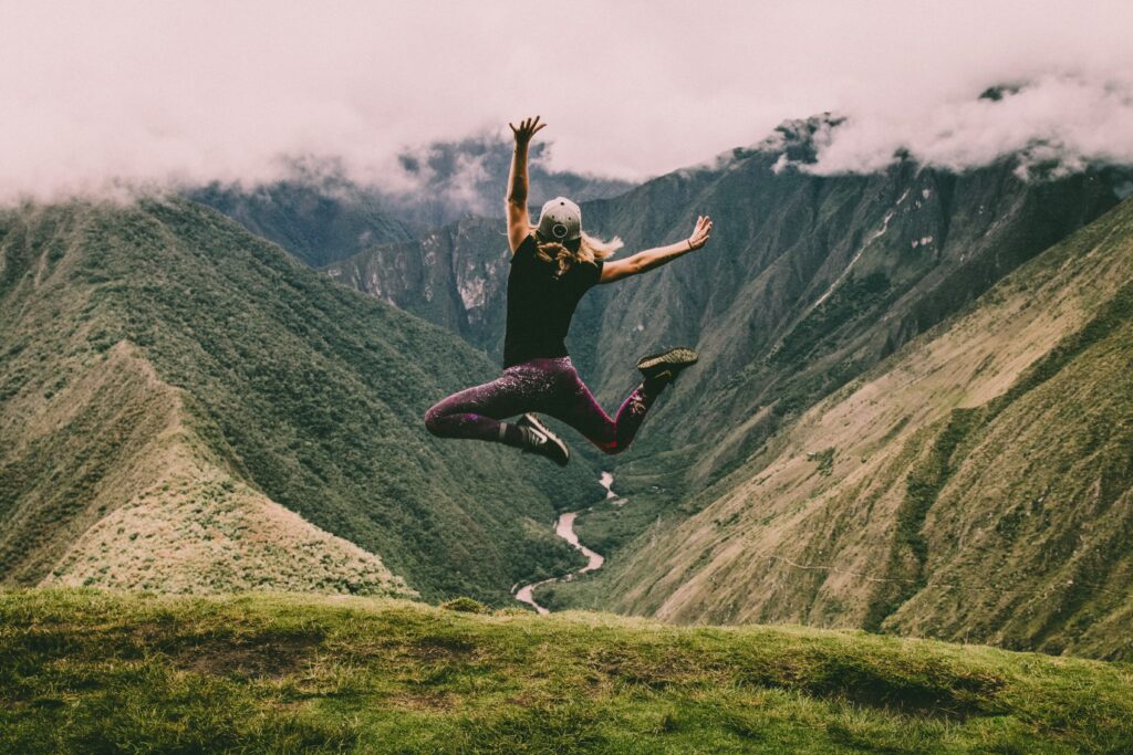 Femme qui saute devant un paysage de montagne. 